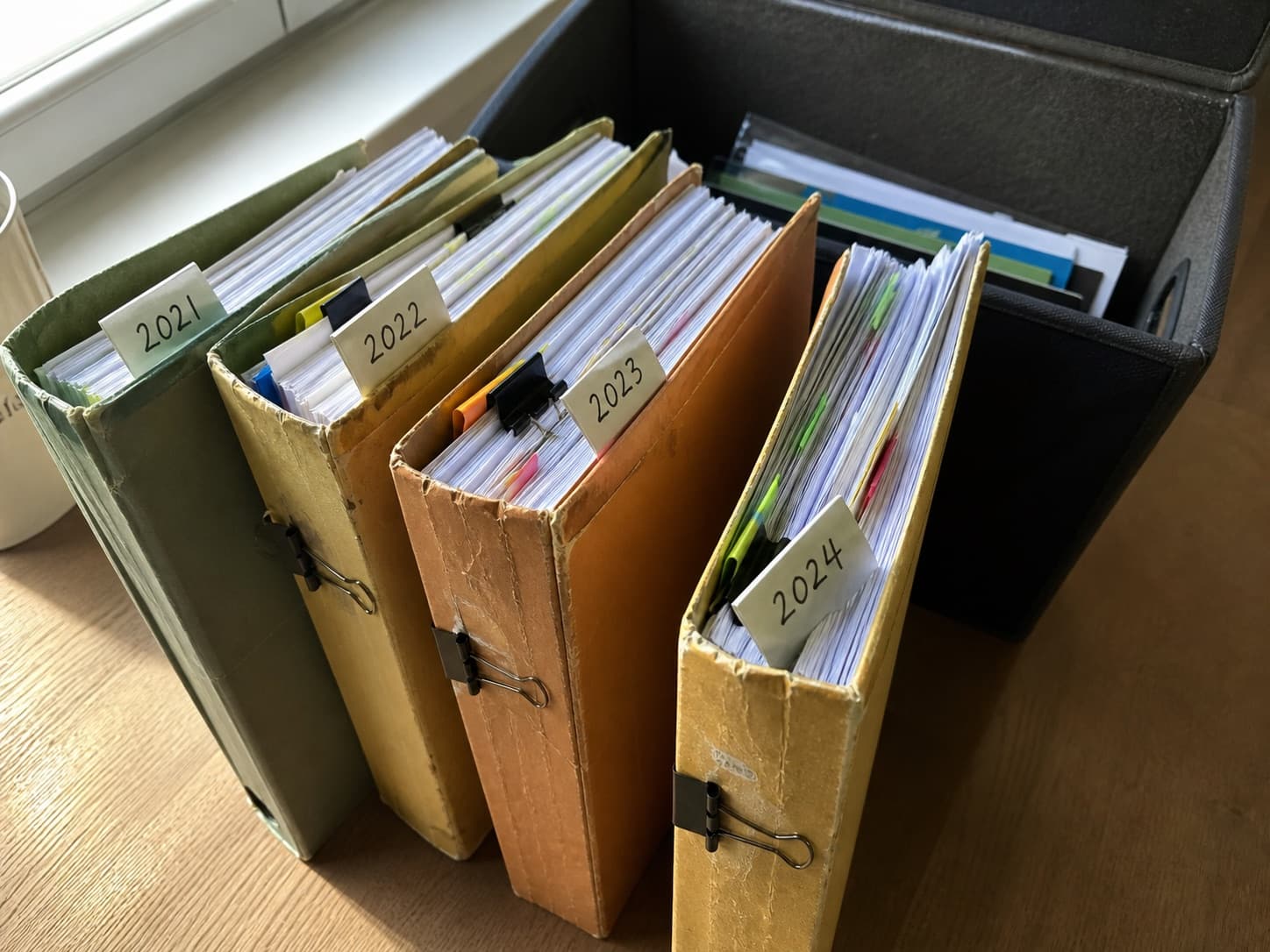 Worn folders organising past papers from 2021 to 2024